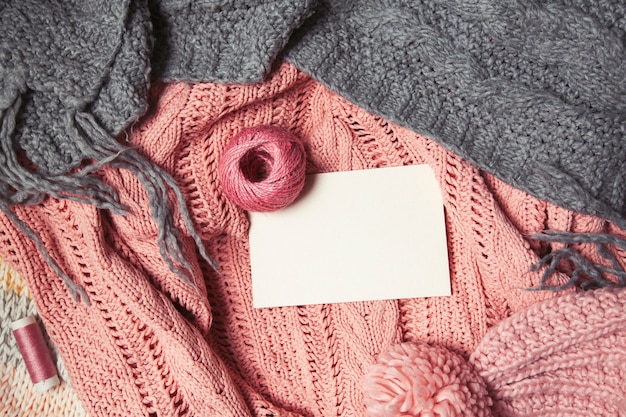 ball of pink wool with white card for text on pink and gray knitted background