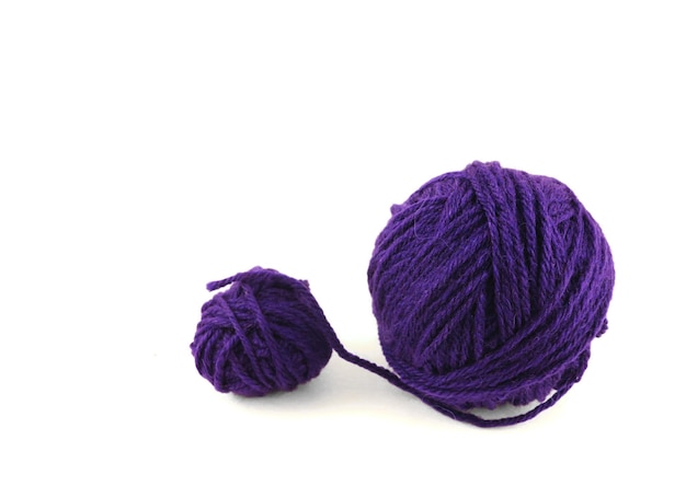 A ball of purple wool and a ball of yarn on a white background.