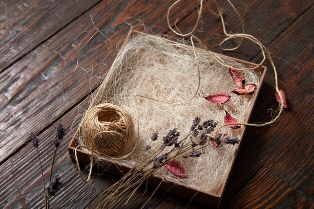 Ball of thread dry petals of flowers and lavender branches on a tray on a wooden table