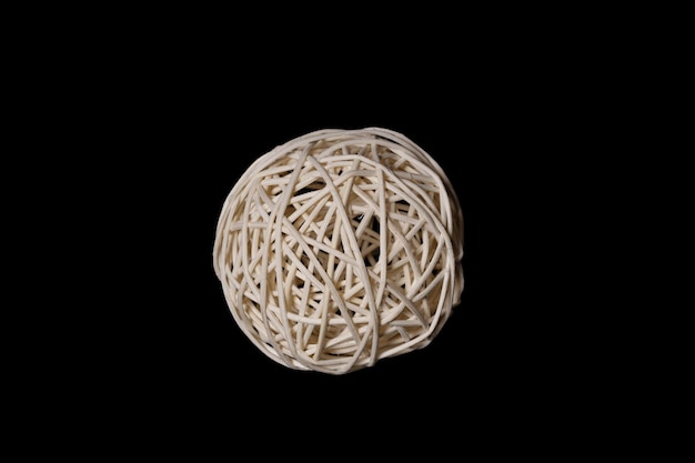 A ball woven from a wooden vine on a black background