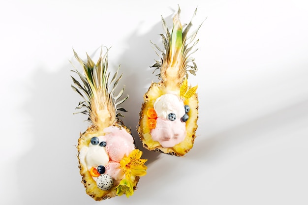 Ballen van ijsdecoratie bloemen en bessen in helften van ananas. Zomer tropisch concept.