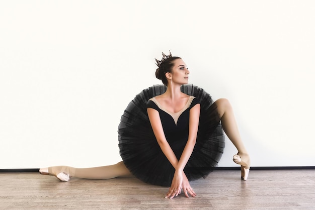 Ballerina in black swan dress against white background Young ballet dancer practicing before performance in black tutu classical dance studio copy space