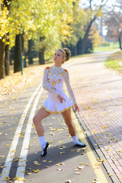 Ballerina dancing in nature park among autumn leaves.