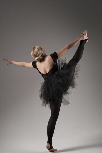 Ballerina Dancing with tutu Modern Ballet Dancer in dancer tutu Gray Background Dancer in Black clothes showing her flexibility posing on gray background in studio