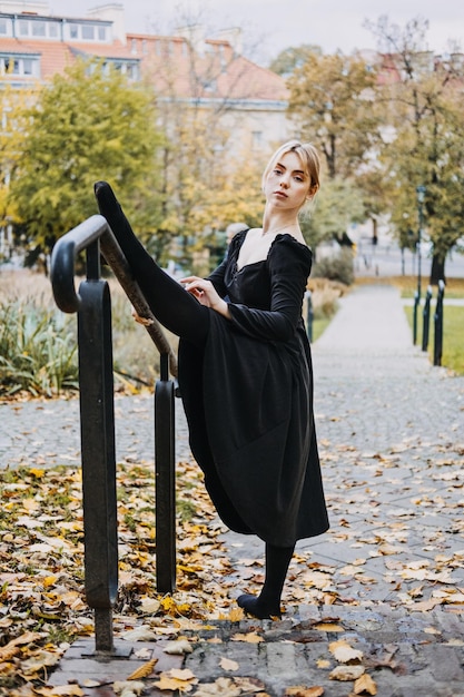 Ballerina dansen in de herfst stad straat moderne balletdanser in zwarte jurk pointe-schoenen buitenshuis