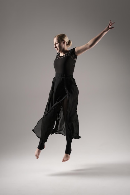 Ballerina dansen met zijde stof moderne balletdanser in fladderende wuivende doek grijze achtergrond