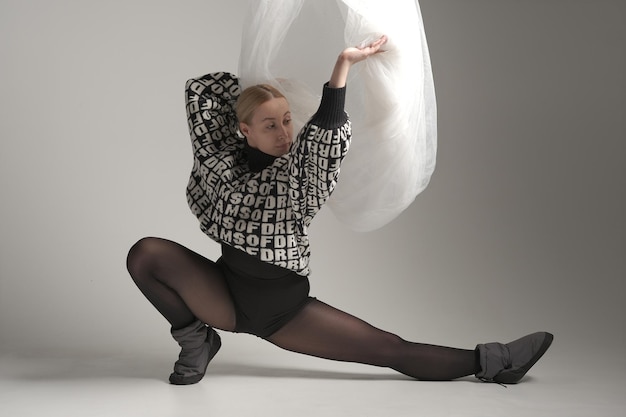 Foto ballerina dansen met zijde stof moderne balletdanseres met wuivende witte stof grijze achtergrond met tekst op trui dreams of