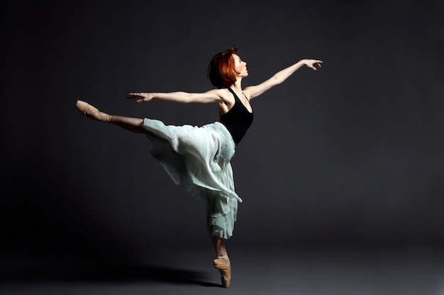 Ballerina danst tegen een grijze achtergrond.