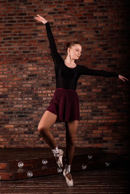 Ballerina in dark bodysuit in dark interior