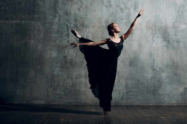 Ballerina female. Young beautiful woman ballet dancer, dressed in professional outfit, pointe shoes and black dress.