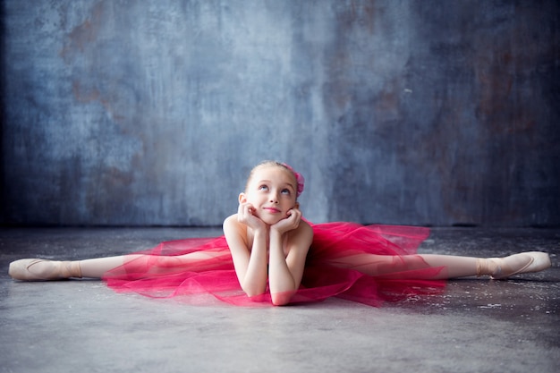 Foto ragazza della ballerina si siede sul pavimento in spaccate