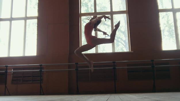 Ballerina performs acrobatics tricks in studio, slow-motion, circus artist - wide angle