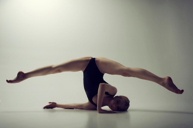 Ballerina sexually demonstrates stretching and plasticity by lifting her legs in a transverse twine while standing on her head