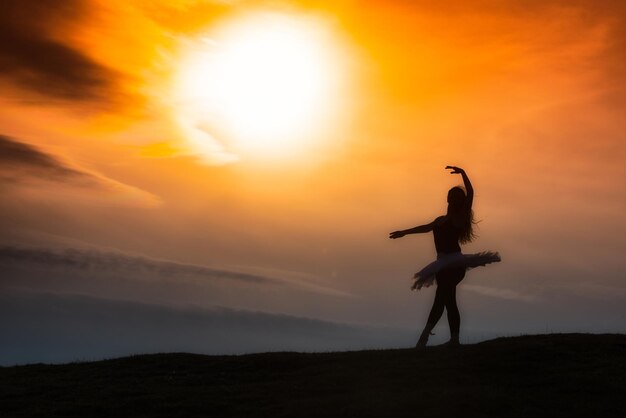 Foto silhouette di ballerina che balla da sola in natura nelle montagne al tramonto