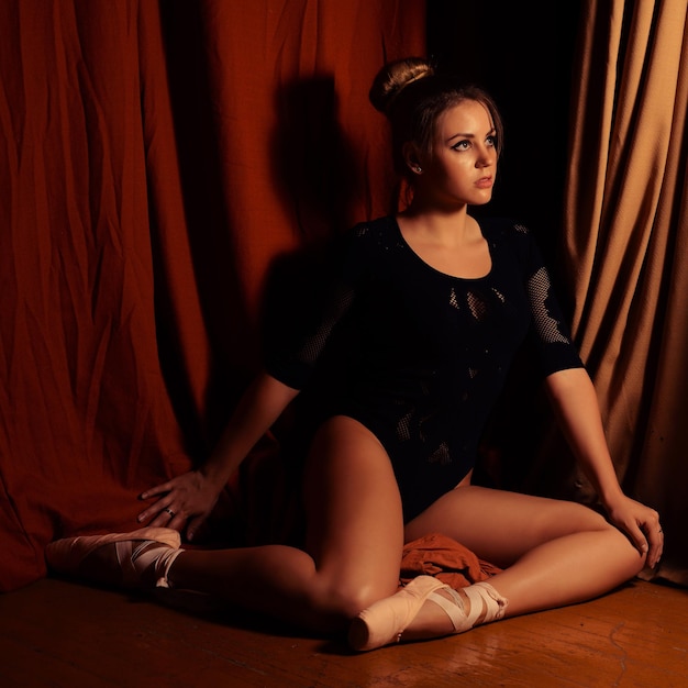 Ballerina sitting on the stage looking at the camera