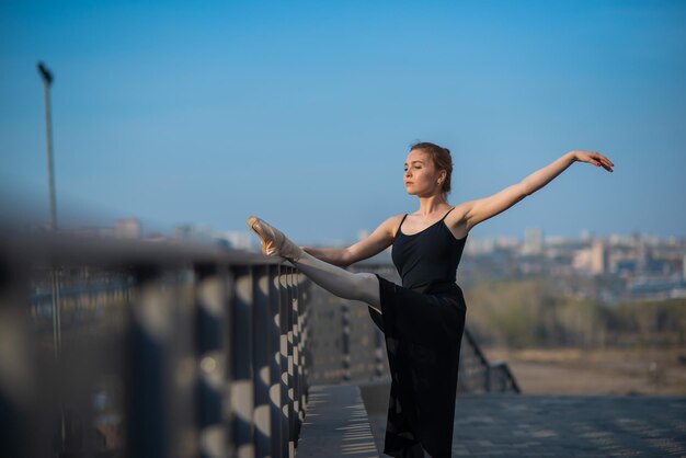 Ballerina in a tutu posing near the fence beautiful young woman in black dress and pointe dancing outside gorgeous ballerina demonstrates amazing stretching