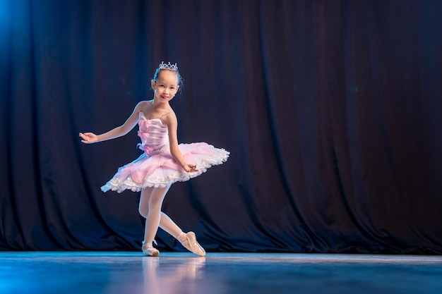 Ballerina van het meisje danst op het podium in witte tutu op pointe-schoenen klassieke variatie.