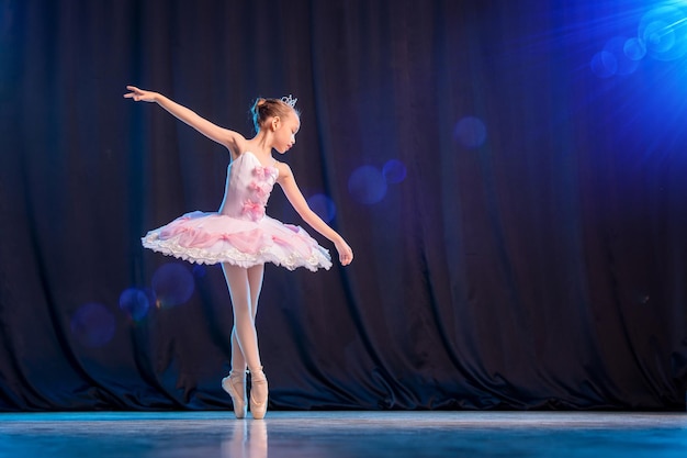 Ballerina van het meisje danst op het podium in witte tutu op pointe-schoenen klassieke variatie.