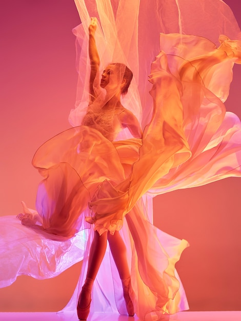 Ballerina young graceful female ballet dancer dancing over red studio beauty of classic ballet