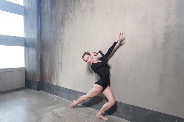 Ballerinabeweging in klassiek ballet poseren in de buurt van raam