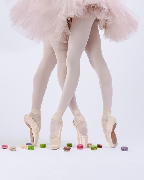 Photo ballerinas legs in pointe shoes and bright sweets macaron cake dance and health choice concept