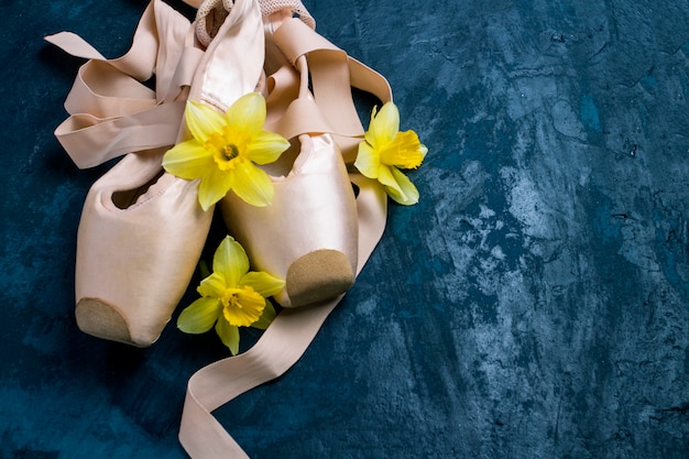 Ballerinaschoenen, pointe-schoenen zonder mensen op een blauwe achtergrond. bloemen van gele narcis.