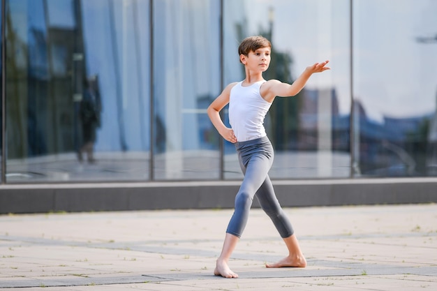 Ballet boy  dancing against the background of reflection of the city in the glass wall