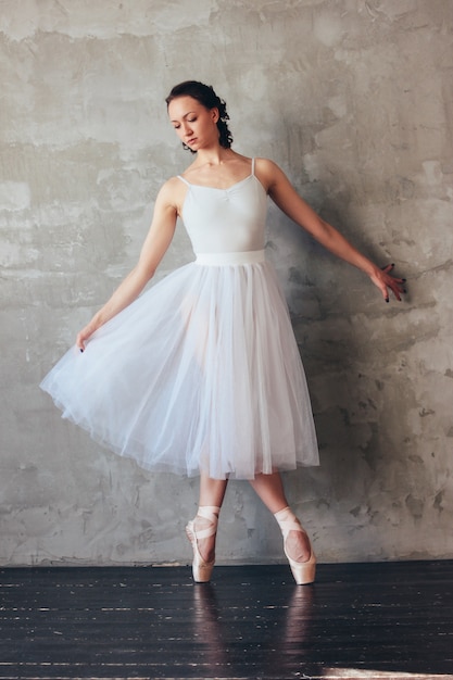 Ballet dancer ballerina in beautiful light blue dress tutu skirt posing in loft studio