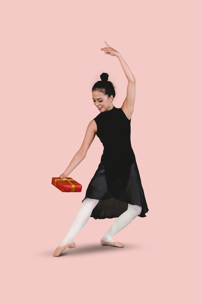 Балетный танцор занимается танцевальным упражнением с подарочной коробкой