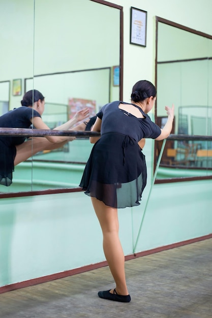 Ballerina di danza classica che si estende in studio di danza ballerina professionista durante la pratica del bailey