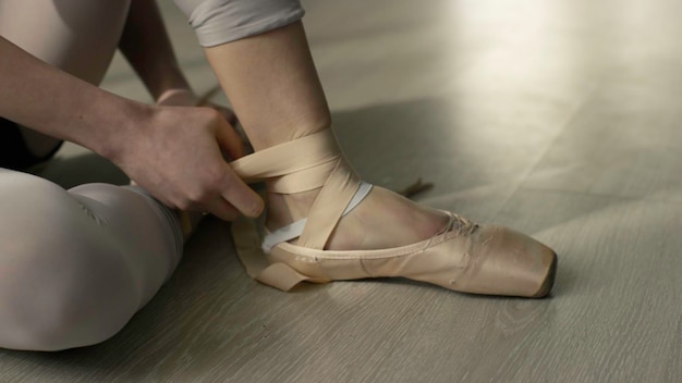 Балетная танцовщица связывает свои кончики Балетный танцовщик связывает балетные туфли перед тренировкой