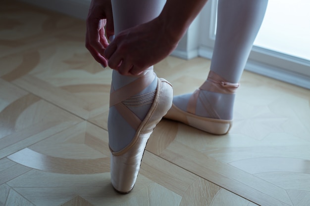 Ballet dancer tying ballet shoes. close-up.