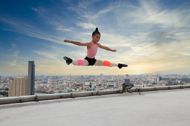 Ballet girl students show jumping skills while performing outdoors on a highrise building