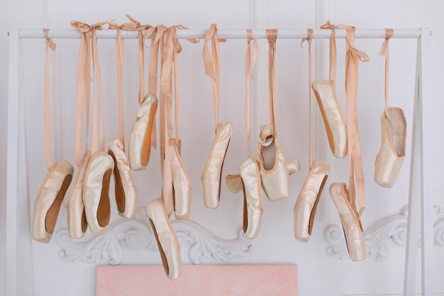 ballet pointe shoes with satin ribbons hanging on ran in room