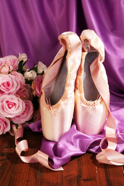 Ballet pointe shoes on wooden floor on fabric background