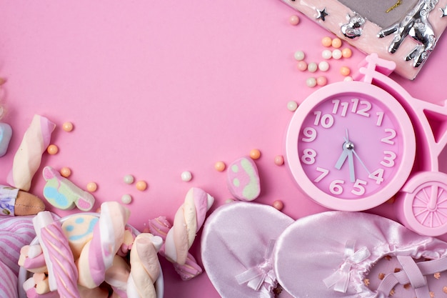 Ballet slippers, sweets and watches on a pink background.