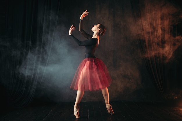 Balletdanser in rode jurk dansen op het podium