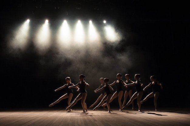 Balletles op het podium van het theater met licht en rook. Kinderen zijn bezig met klassieke oefeningen op het podium.