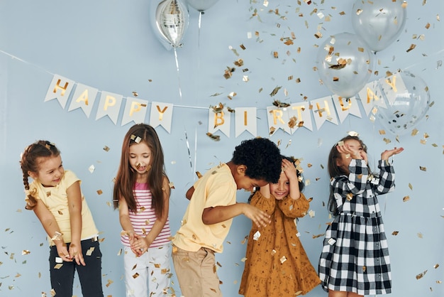 Ballonnen en confetti Kinderen die een verjaardagsfeestje binnenshuis vieren, hebben samen plezier