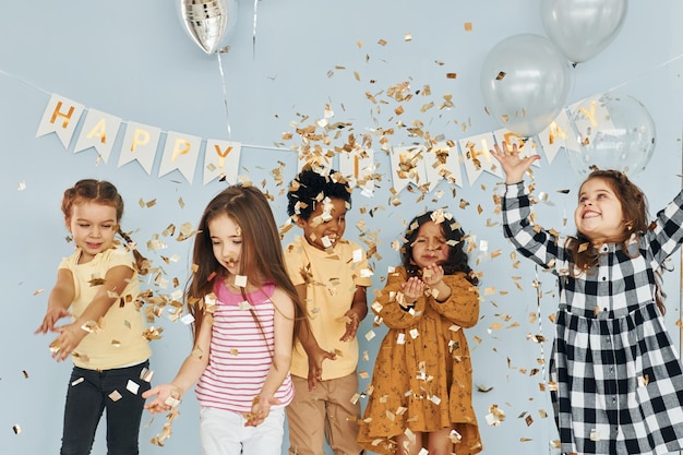 Ballonnen en confetti Kinderen die een verjaardagsfeestje binnenshuis vieren, hebben samen plezier