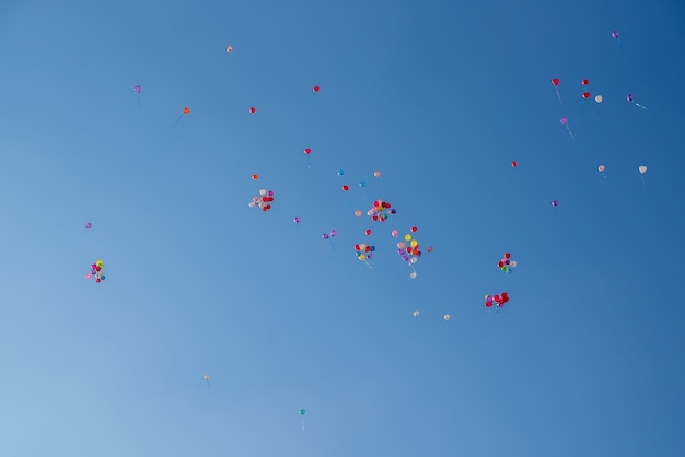 Ballonnen van verschillende kleuren vliegen in de blauwe lucht