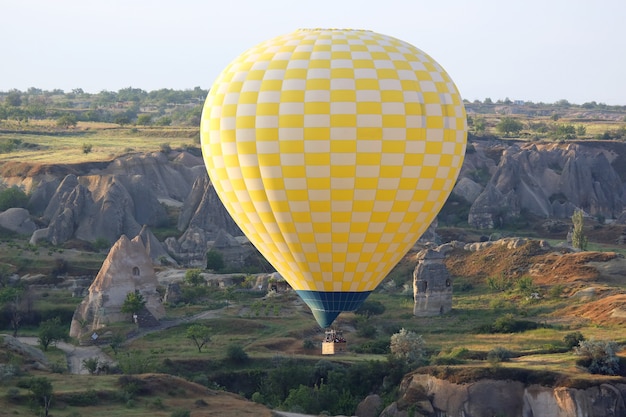 Balloon is flying in mountainous area in Cappadocia