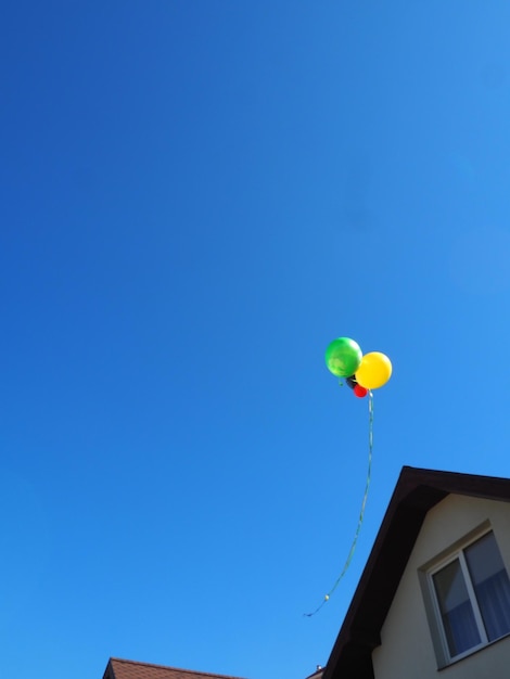 A balloon is flying in the sky and the sky is blue.