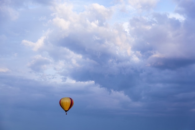 Воздушный шар с корзиной, наполненной горячим воздухом, летит в голубом небе. Воздушный шар в голубом небе.