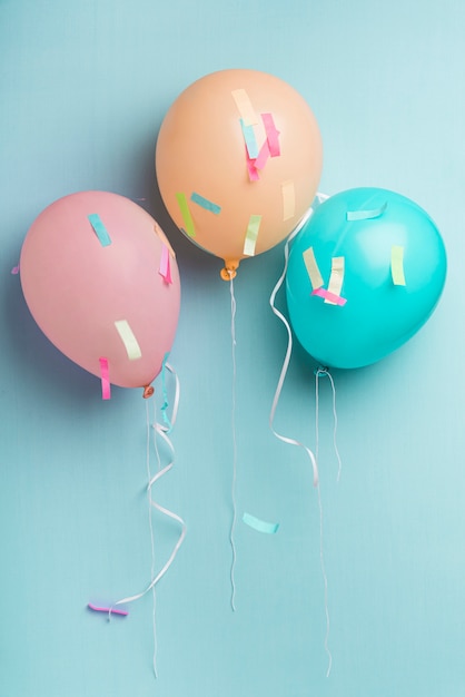 Photo balloons and confetti on blue background with copy space