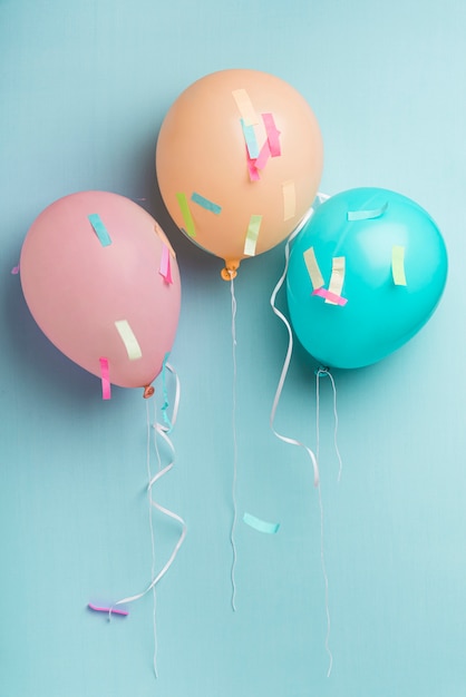 Balloons and confetti on blue background with copy space