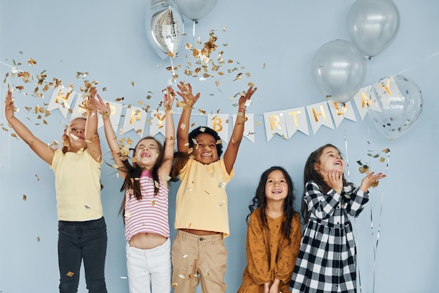 Photo balloons and confetti children on celebrating birthday party indoors have fun together