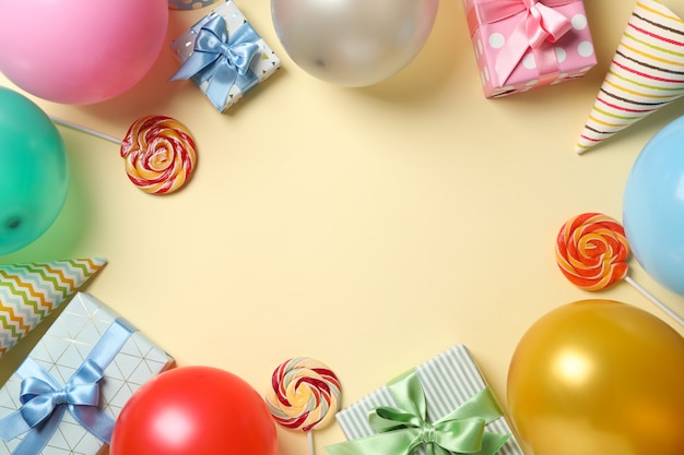 Balloons, gift boxes, lollipops and birthday hats on color background, space for text