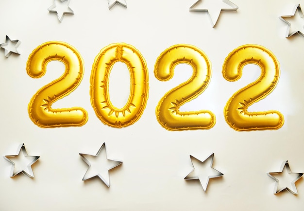 Photo balloons made of gold foil 2022 on a white background. metallic shapes of stars.christmas and new year.