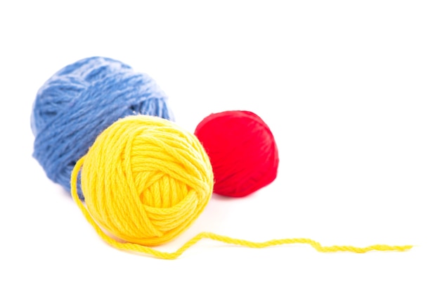 Balls of blue, red and yellow woolen threads on the white background